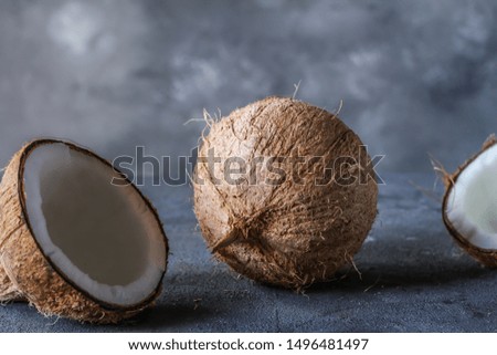 Photo of fresh coconut on a table. Tropical palm fruits. Coconut cut in half. Beach fruit. Retro dark background. Rustic wooden board. Front view. Image