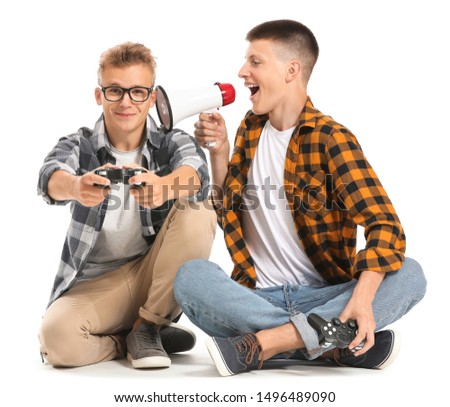 Teenage boys with video game controllers and megaphone on white background