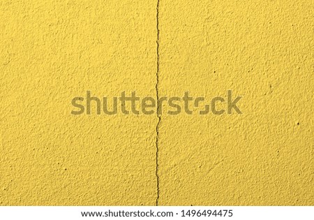 Fragment of an old yellow concrete wall with cracks
