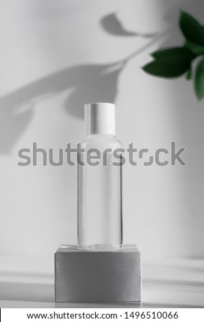 Makeup remover, natural moisturizing lotion mockup close up. Transparent liquid container side view. Organic cosmetics poster concept. Micellar water bottle and blurred leaves on background Royalty-Free Stock Photo #1496510066