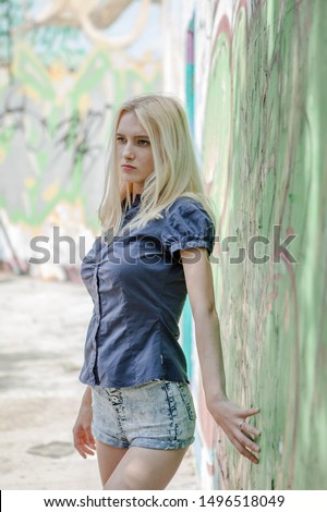 Young girl blonde poses on a background of a wall with graffiti