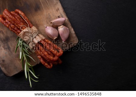 Rural meat. Thin sausages with garlic on a dark background