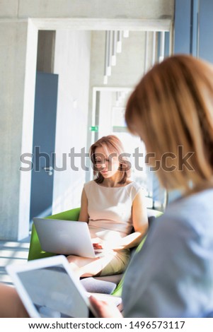 Businesswomen working while waiting in office lobby