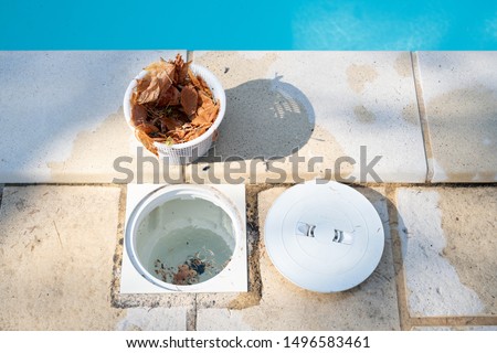 Removing a pool skimmer basket to empty the leaves out Royalty-Free Stock Photo #1496583461