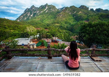 Young woman looking at a big mountain range  on a balcony