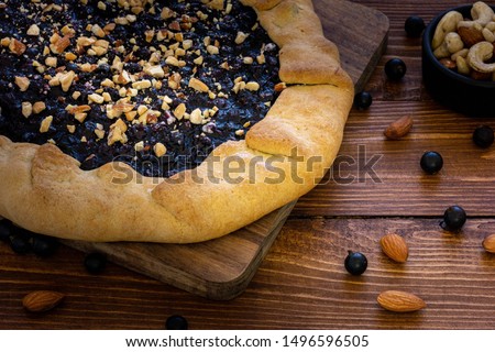 Homemade holiday cake with currant berries sprinkled with nuts baked to the autumn Thanksgiving holiday on a wooden table or background.