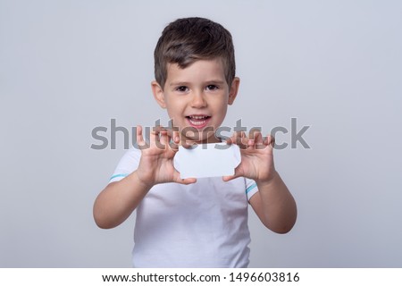 Child showing empty blank paper, copy space. Kid holding bank card in hands. Universal template of a white bank or gift card. Ready to used in your design.