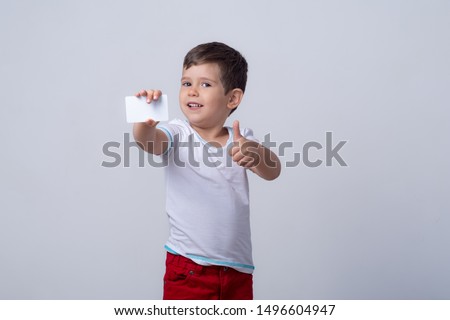 Child showing empty blank paper, copy space. Kid holding credit card in hands. Realistic white mockup of a bank or gift card. Ready to used in your showcase.
