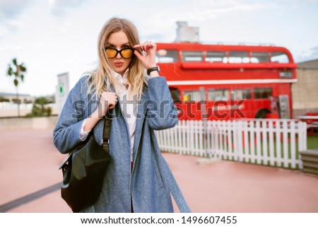 Outdoor fashion image of stylish young woman posing at London street , elegant casual business outfit, sending kiss and looking on camera , autumn spring mid season time, toned colors.