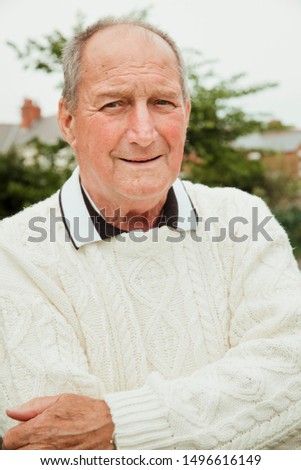 A portrait of a senior man smiling at a bowling green.