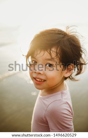 Portrait of young little Asian boy child in the sunset. Early learning. School holiday. Fun activity. Close up image. Golden hour. Kid with long hair. Childhood memory. Tanjung Aru, Sabah beach