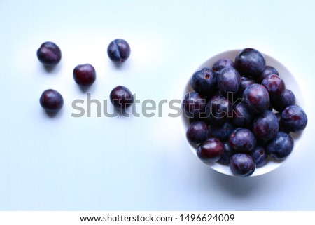 Сomposition of ripe blue plums in a vase shot closeup