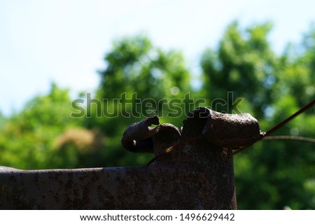 Old rusty post made of iron rails with grass. Outdoor landscape low angle view, selective focus