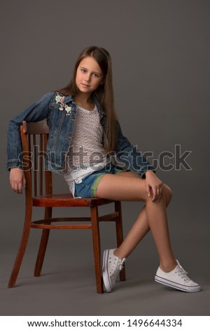 Teenage girl in a denim jacket sitting on a rare chair