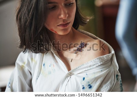 Little flower on the skin. Young creative woman is in art studio. Conception of painting.