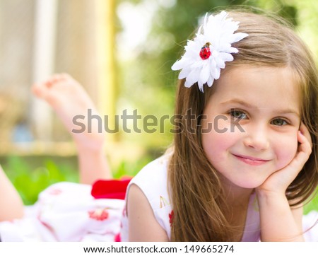 Portrait of a smiling little girl lying on green grass Royalty-Free Stock Photo #149665274