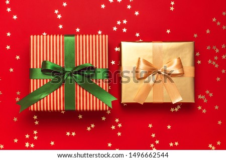 New Year Christmas presents with green ribbon, golden gift, confetti stars on red background top view. Flat lay Xmas holiday 2020 celebration. Gift boxes greeting card Festive decorations