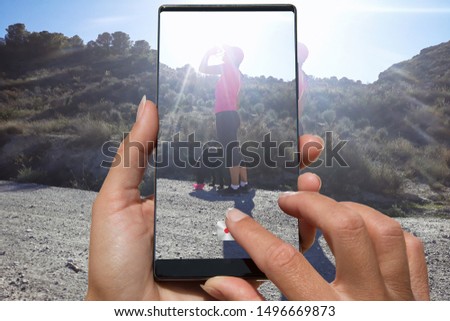 Woman photographing on cell phone sport dressed woman drinking water on walk with a dog outdoors in nature.