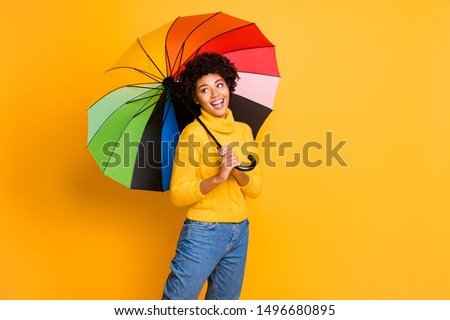 I like rainy weather concept. Photo of positive cheerful excited emotional singing teenager covering herself with multicolored accessory looking at wet city street having a walk isolated background