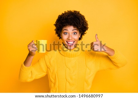 Photo of cheerful charming nice cute excited rejoicing funny black american girlfriend holding cup with her hand and thumbing up to give feedback wearing pullover isolated vibrant color background