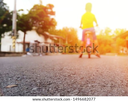 A boy standing with a bicycle in the middle of the road By waiting for his father to return home (picture blurred)