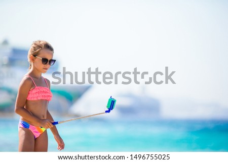 Kid taking selfie by her smartphone on the beach vacation