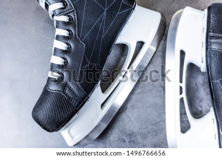Men's hockey black and white skates on a gray background. The concept of winter sports, men's hobbies, amateur sports. Close-up, minimalism, flat lay, top view.