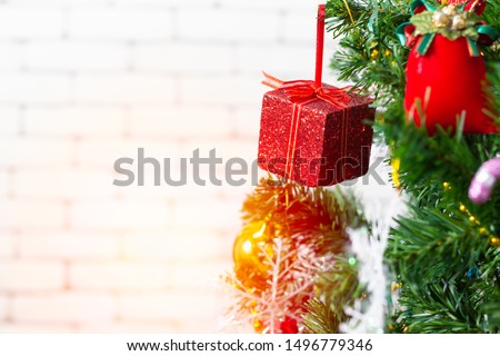 A red gift box hanging on a Christmas tree. Ideas to welcome the upcoming Christmas season.