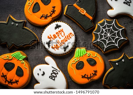 Halloween Gingerbread Cookies - pumpkin, ghosts, witch hat, spiderweb on black background. Top view.