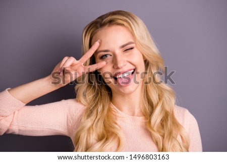 Close-up portrait of her she nice attractive lovely funky girlish cheerful cheery positive wavy-haired girl showing tongue out v-sign near eye isolated over gray violet purple pastel color background