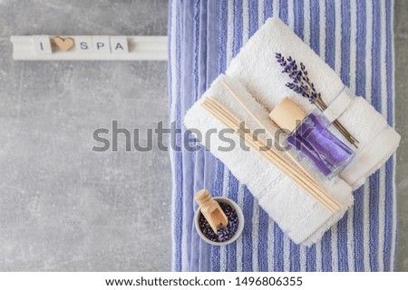 Twisted bath towel with air freshener and wooden letters spelling " I love SPA" on light gray textured background. Minimalism, soft focus, copy space, top view. SPA concept.