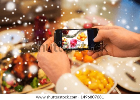 technology, eating and holidays concept - close up of male hands photographing food by smartphone at christmas dinner over snow