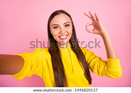 Self portrait of cheerful cute pretty sweet lovely fascinating girlfriend brunette haired showing you ok sign taking selfie wearing yellow sweater while isolated over pink pastel color background