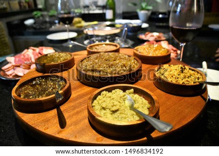 Appetizers served in wooden jars with a glass of red wine.