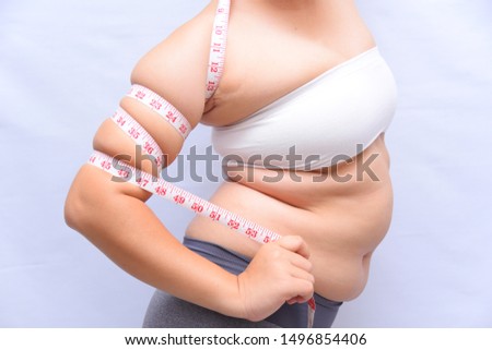 Beautiful fat woman She uses a tape measure to measure her arms on a white background. She wants to lose weight the concept of surgery and break down the fat underneath. Royalty-Free Stock Photo #1496854406