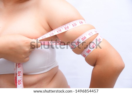 Beautiful fat woman She uses a tape measure to measure her arms on a white background. She wants to lose weight the concept of surgery and break down the fat underneath. Royalty-Free Stock Photo #1496854457