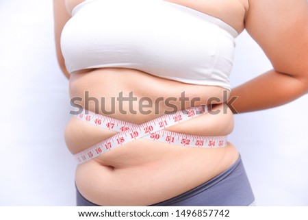 A beautiful fat woman with a tape measure, using her hands to hold the tape measure, the belly measure in the form of a cross on a white background She wants to lose weight the concept of surgery and. Royalty-Free Stock Photo #1496857742