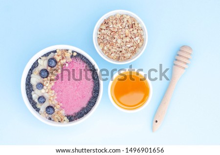 Smoothie bowl with fruits and granola and honey on a blue background. 