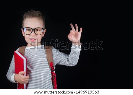 Cheerful smiling little boy on a black background. Looking at camera. School concept. Place for text