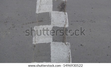 white and gray speed bump rolled up in the asphalt in summer