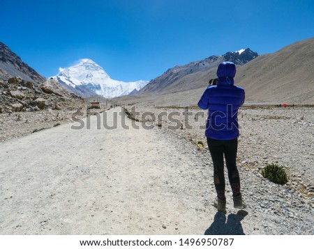 CLOSE UP: Unrecognizable woman takes photos of windswept Everest from Base Camp. Young female photographer stops during a trek along the scenic gravel path to take stunning photos of Mount Everest.