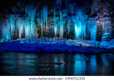 Close up Stunning frozen waterfall icicles  on winter day. Winter cascade frozen into numerous white icicles. Waterfall falling past hundreds of icicles.  Royalty-Free Stock Photo #1496951336
