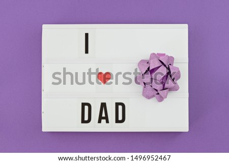 Happy Fathers Day flat lay. Lightbox with text i love dad on purple background with red heart. Greeting card to celebrate Father's day
