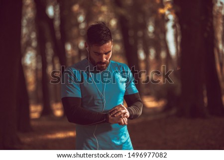 Urban runner man looking app on sportwatch. Male running jogging smart watch outside. Royalty-Free Stock Photo #1496977082