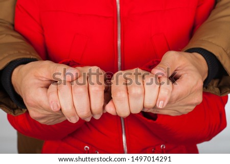 Close up picture of young couple holding hands, wearing red and brown winter coat