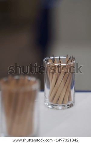 Glass Cup with brown and black pencils on the glass table. Close up. Copy space.