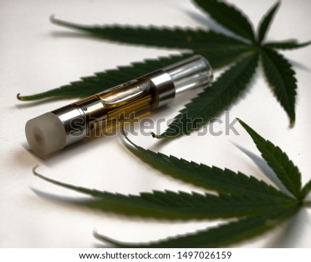 A CBD oil vape cartridge with hemp leaves on white background.