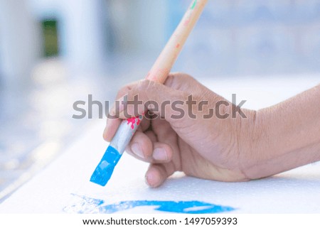 The hand is holding the brush to write the letter on the sign