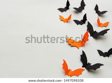 halloween  concept - black and orange paper bats flying over grey background