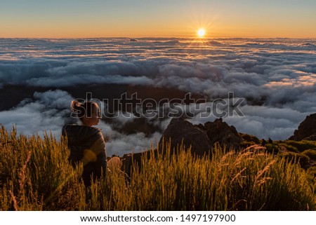 Woman sitting on a summit watching the sunrise over the fluffy clouds Royalty-Free Stock Photo #1497197900